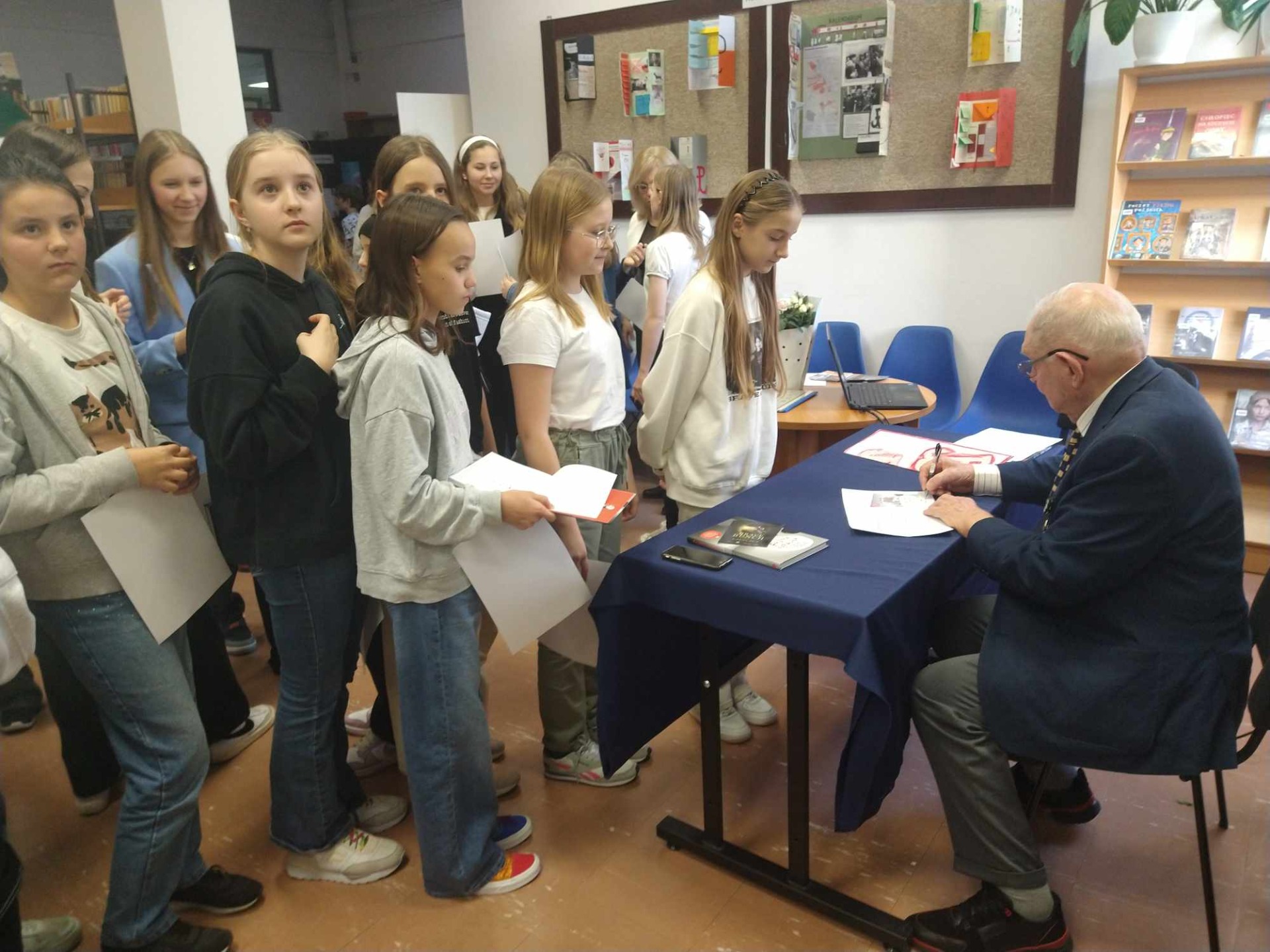 Dzieci klas 5 i 6 czekają na autograf od Pana Bogusława Kamili - uczestnika Powstania Warszawskiego