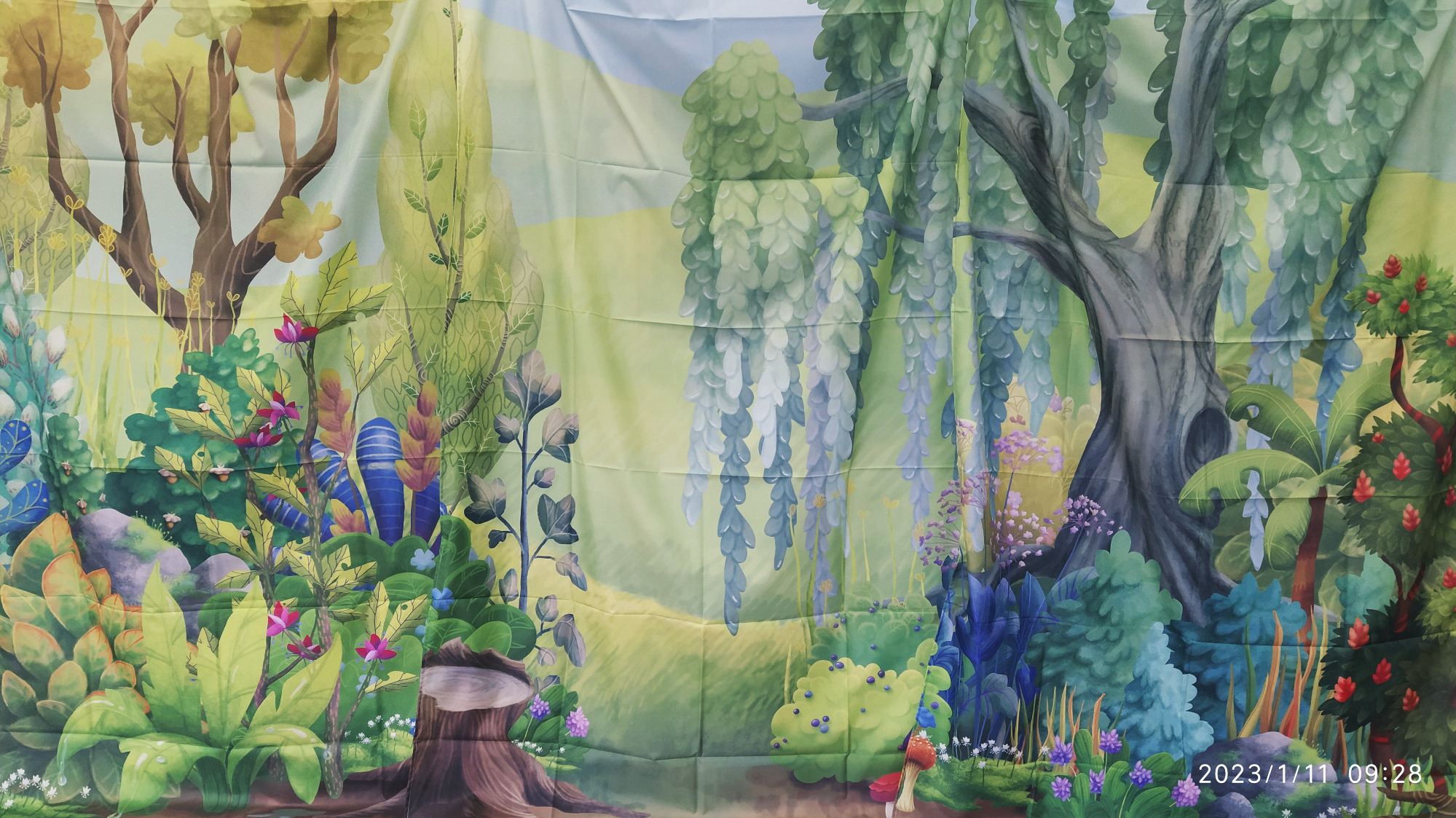 Kurtyna teatralna- tło las: drzewa, kolorowe krzewy, kwiaty.