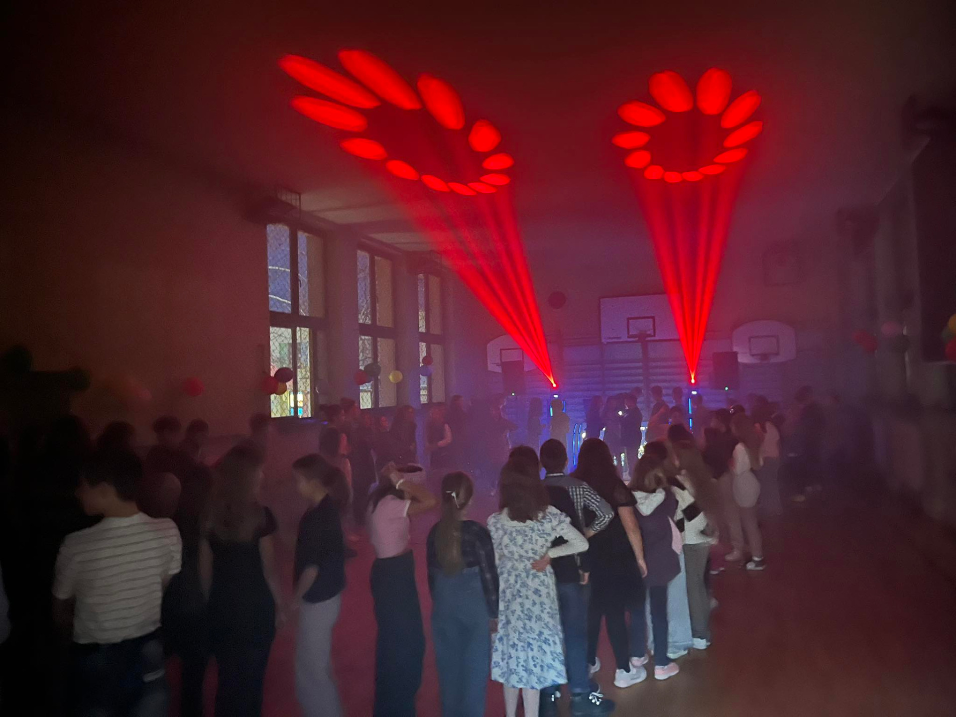 Uczniowie tańczący w sali gimnastycznej podczas zabawy andrzejkowej.