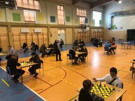 Zdjęcie przedstawiające uczestników rozgrywających partie szachowe 