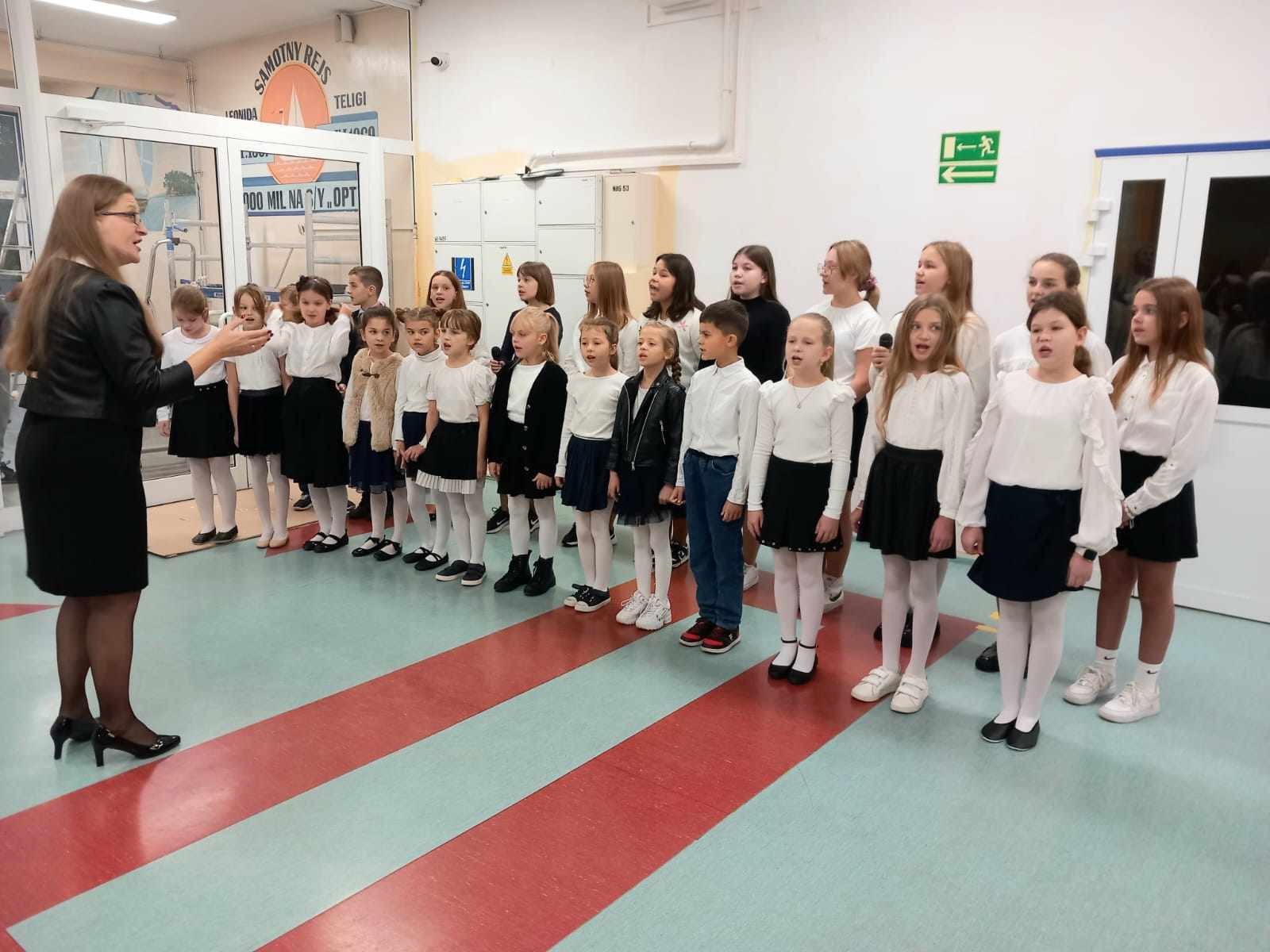 Chór szkolny pod przewodnictwem pani Klaudii Szczepkowskiej śpiewa przy wejściu do szkoły.