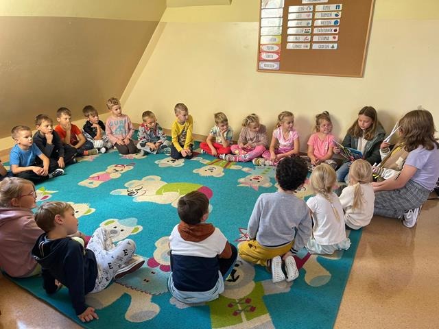 dzieci na dywanie słuchają