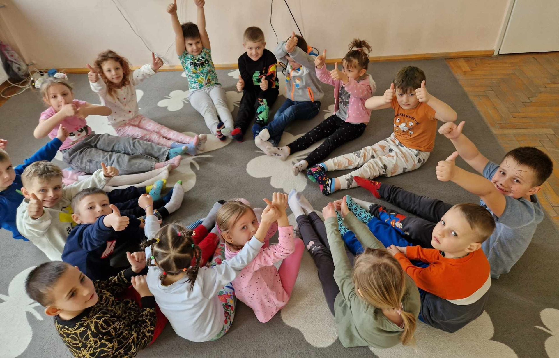 Dzień Kolorowej Skarpetki. Dzieci z oddziału 0A siedzą w kręgu, prezentują swoje kolorowe skarpetki.