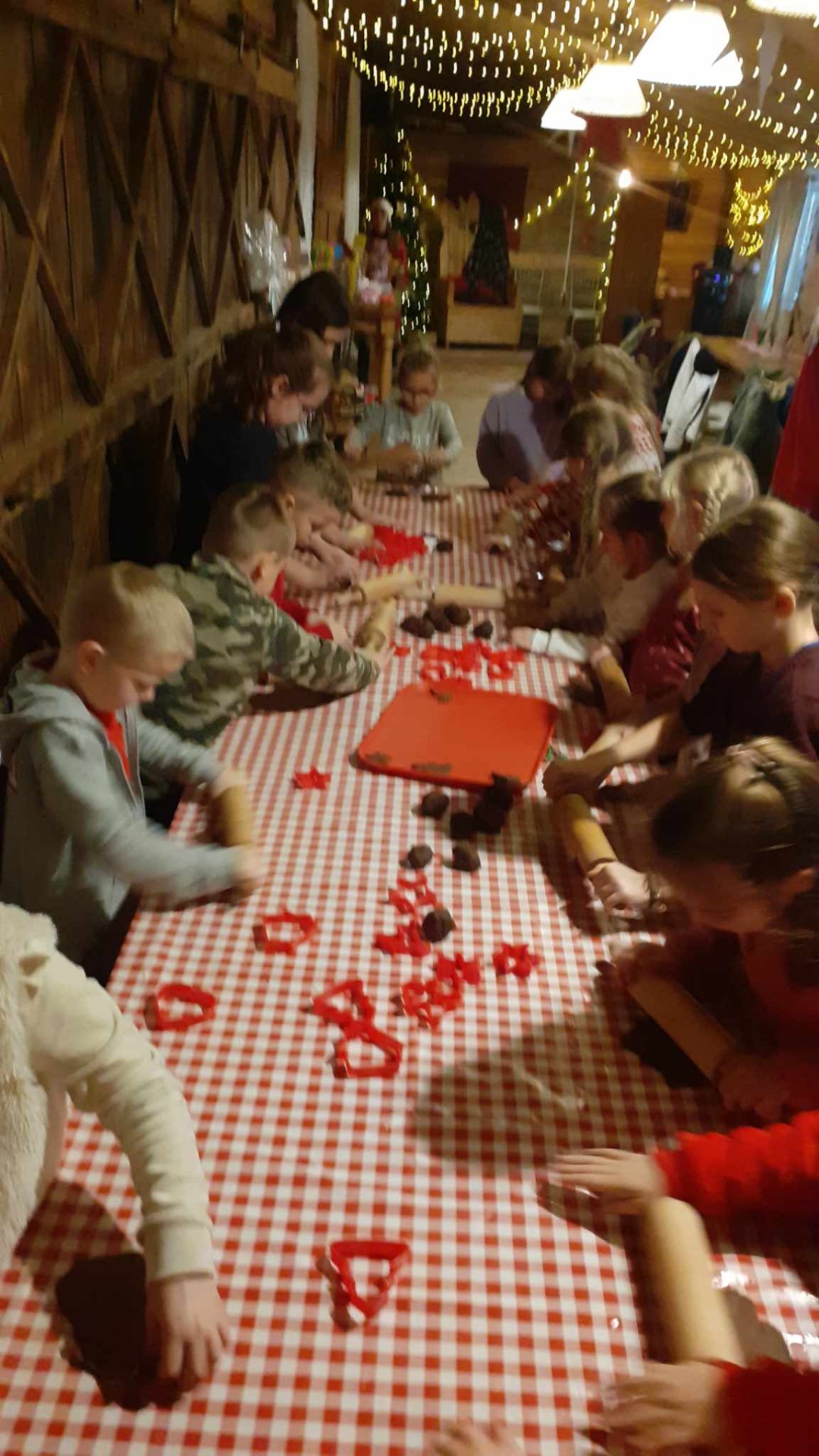 Uczniowie przy długim stole uczą się robienia pierników.