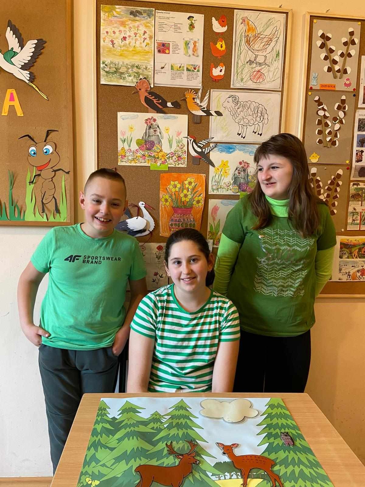 3 uczniów ubranych na zielono pozuje do zdjęcia